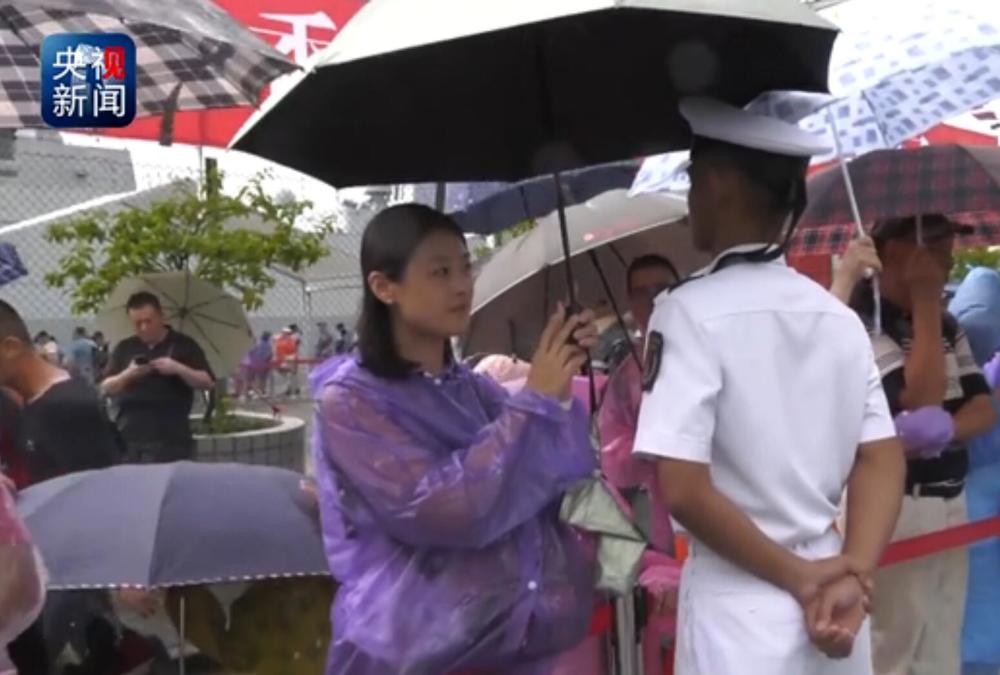 Hong Kong citizen holds umbrella for PLA guard in rainstorm