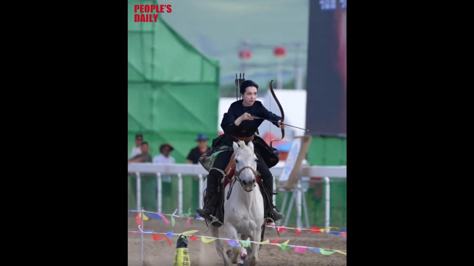 Young woman horseback rides and shoots at Naadam Festival