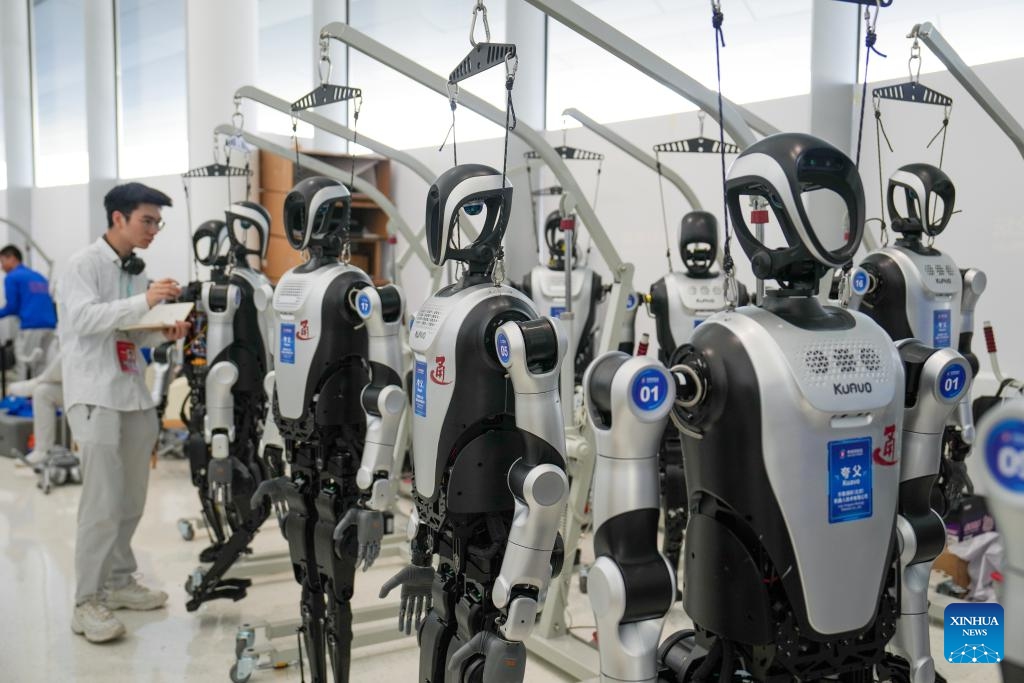 A machinist debugs humanoid robots at Zhongguancun International Innovation Center, venue for the 2025 Zhongguancun Forum (ZGC Forum) Annual Conference, in Beijing, capital of China, March 27, 2025. Themed New Quality Productive Forces and Global Technology Cooperation, this year's annual conference of the forum showcases the latest technologies and products on humanoid robots. (Photo: Xinhua)
