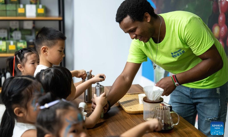 A volunteer grinds coffee beans with children during a hands-on experience session at the Ethiopia pavilion of a permanent exhibition hall of the China-Africa Economic and Trade Cooperation Promotion Innovation Demonstration Park in Changsha, central China's Hunan Province, Aug. 30, 2024. Various activities promoting youth communication between China and Africa were organized here during the summer vacation. With the help of African volunteers from local universities, Chinese students were able to feel the charm of African culture by learning traditional African dance, music, folk arts, and making immersive tours of African customs via VR devices. Photo: Xinhua