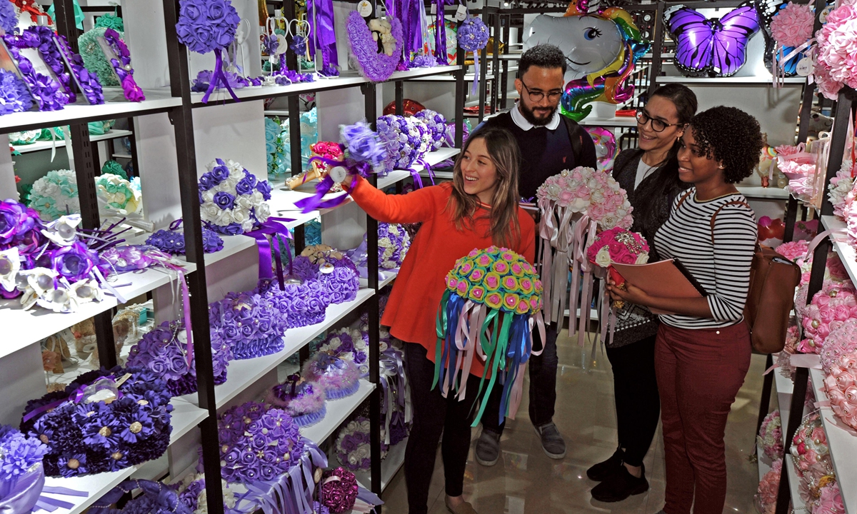A merchant (L) from Colombia introduces wedding decorations to purchasers in Yiwu, east China's Zhejiang Province, Oct. 22, 2018. (Photo:Xinhua)